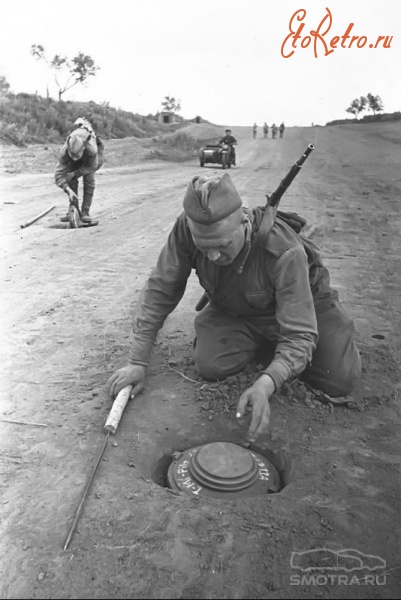 Солдаты и офицеры Советской армии - Советские сапёры обезвреживают немецкие противотанковые мины «Теллермина-43» (Tellermine Pilz 43) на дороге.