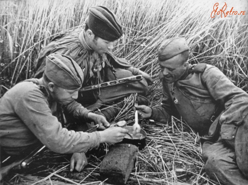 Солдаты и офицеры Советской армии - Трое советских солдат-гвардейцев, вооруженных ППШ, едят из одного котелка.
