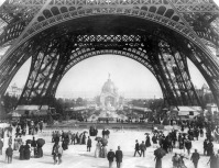 Париж - Paris Exposition, view from ground level of the Eiffel tower with Parisians promenading Франция