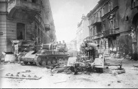 Вильнюс - Советская САУ СУ-76М проезжает мимо разбитого 88-мм немецкого зенитного орудия FlaK в Вильнюсе