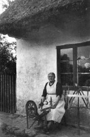 Калининградская область - Черняховский р-н, Ельники. Бабушка с прялкой перед домом.