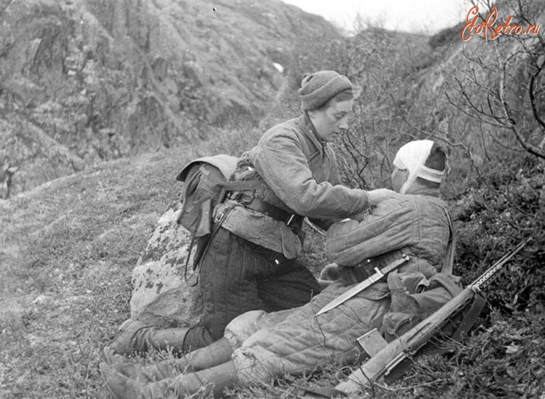 Россия - Сандружинница Зорина Н., награжденная орденом Красного знамени, перевязывает раненого бойца на поле боя