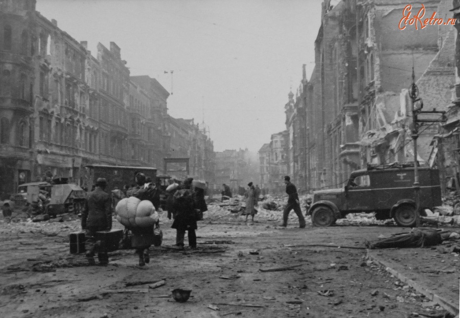 Берлин - Немецкие мирные жители идут по разрушенной улице Берлина.