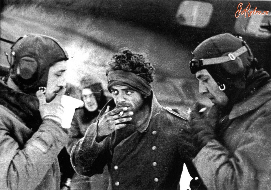 Войны (боевые действия) - Раненый немецкий солдат курит с лётчиками перед отправкой в тыл из-под Сталинграда.